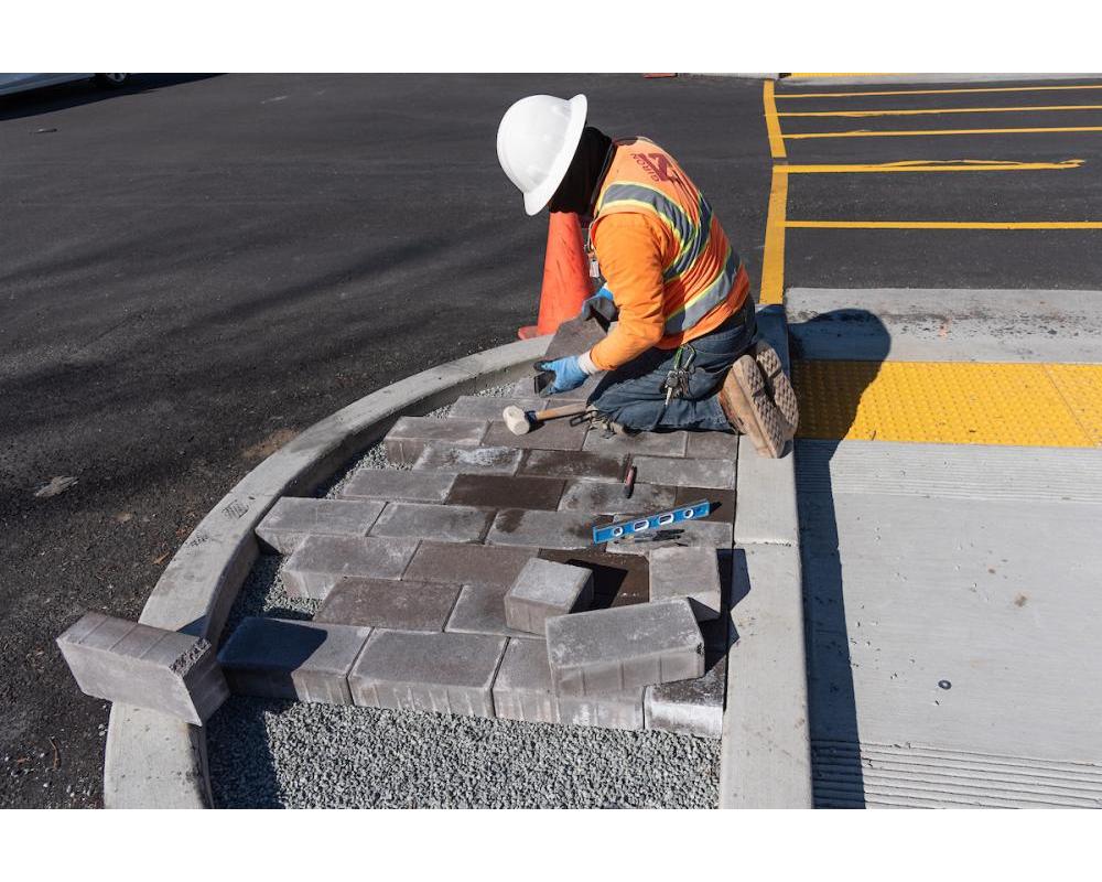 Image of worker installing pavers at a new median refuge at Geary and Steiner
