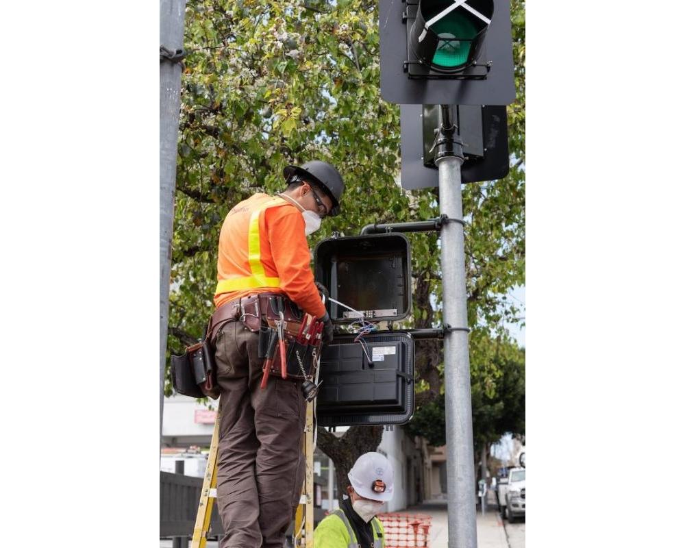 Photo of A crew member programming a pedestrian signal on a recently-installed traffic signal on Van Ness.