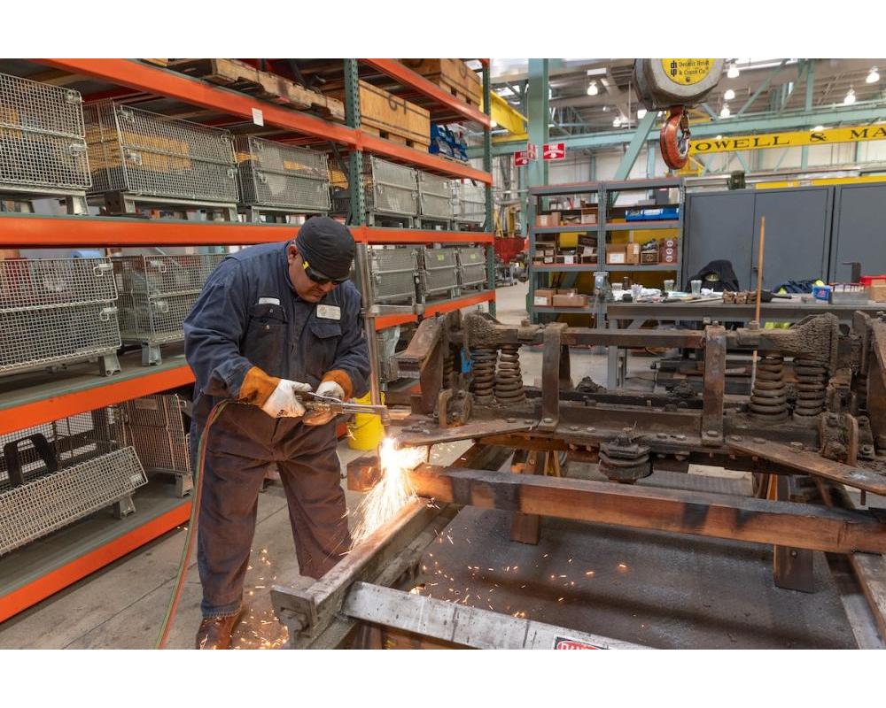 Worker welding a metal cable car frame