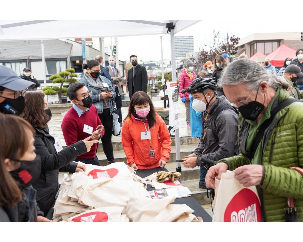 SFMTA staff hand out Muni bags to guests at the Geary Rapid ribbon cutting event