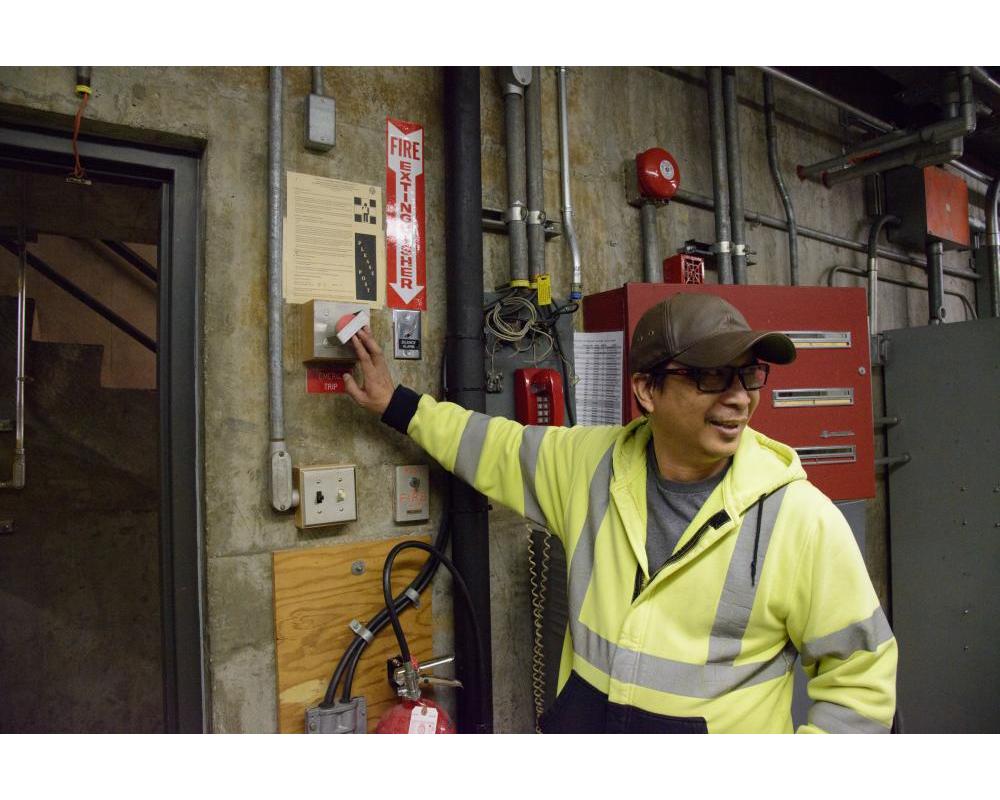 Crew member looking away while holding a wall switch inside a systems shop location.