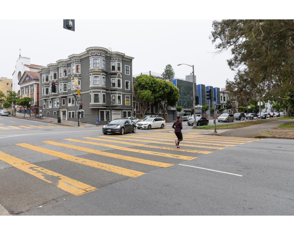 Person in the crosswalk while cars turn left from Oak Street onto Masonic Avenue