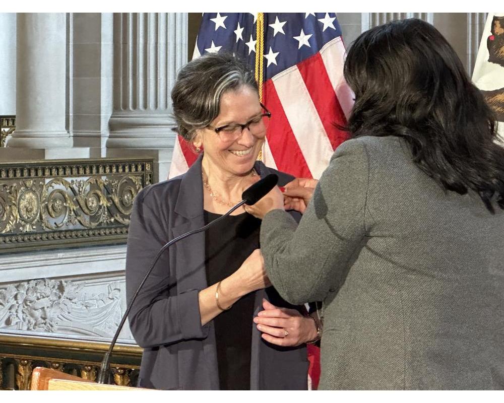 SFMTA Board of Directors Member Janet Tarlov receiving a pin at a ceremony.