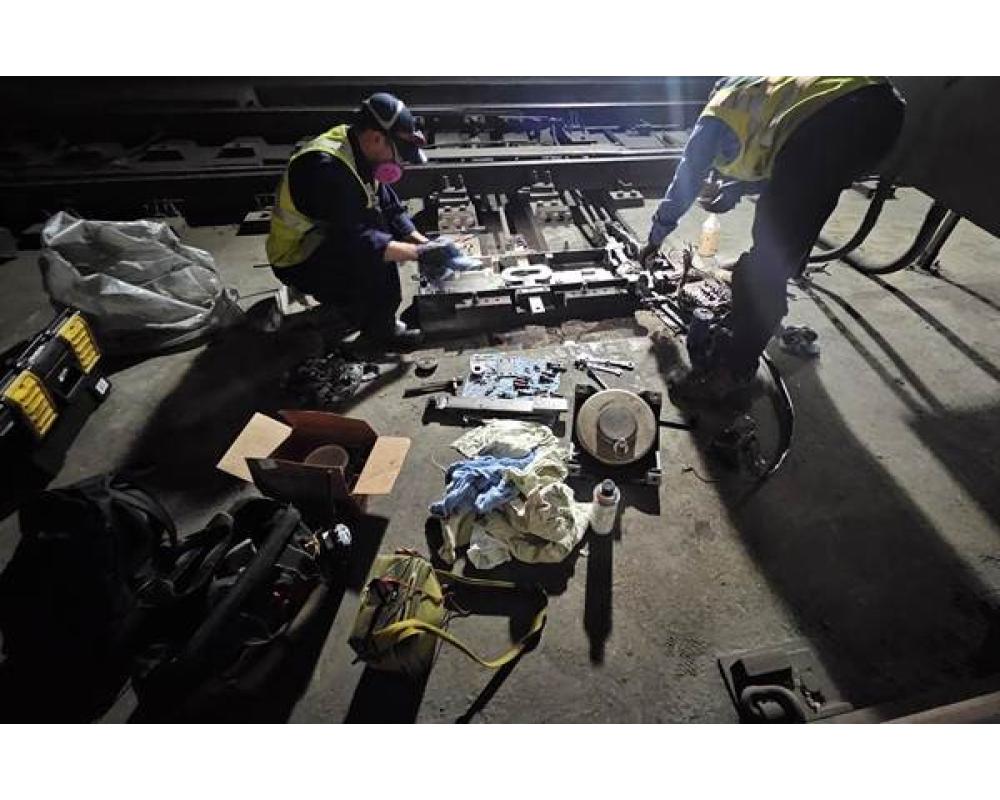 Two crew members hover over a range of materials to do subway and surface switch repairs during Fix-It Week.