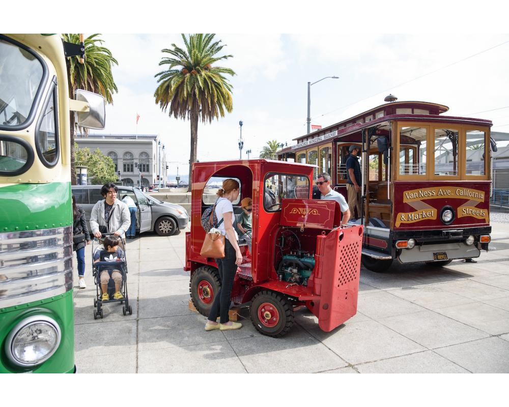 Family enjoying Muni Heritage Weekend's interactive installations: Vintage cars and Mini truck
