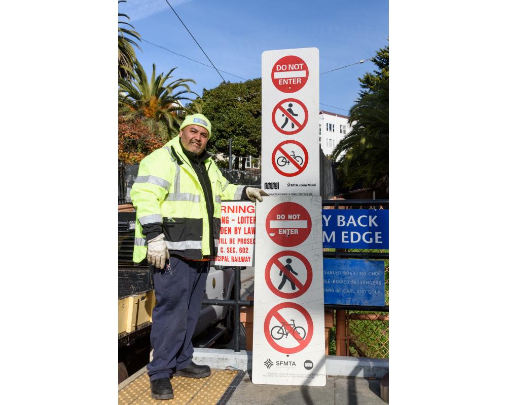SFMTA staff stands near signs upgrade for a Fix It! program.