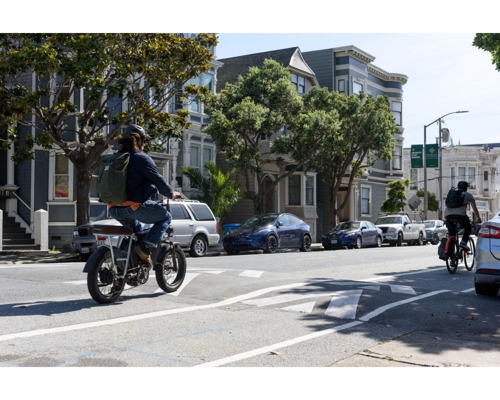 People biking on a road that has a speed hump, a raised section to slow down traffic,