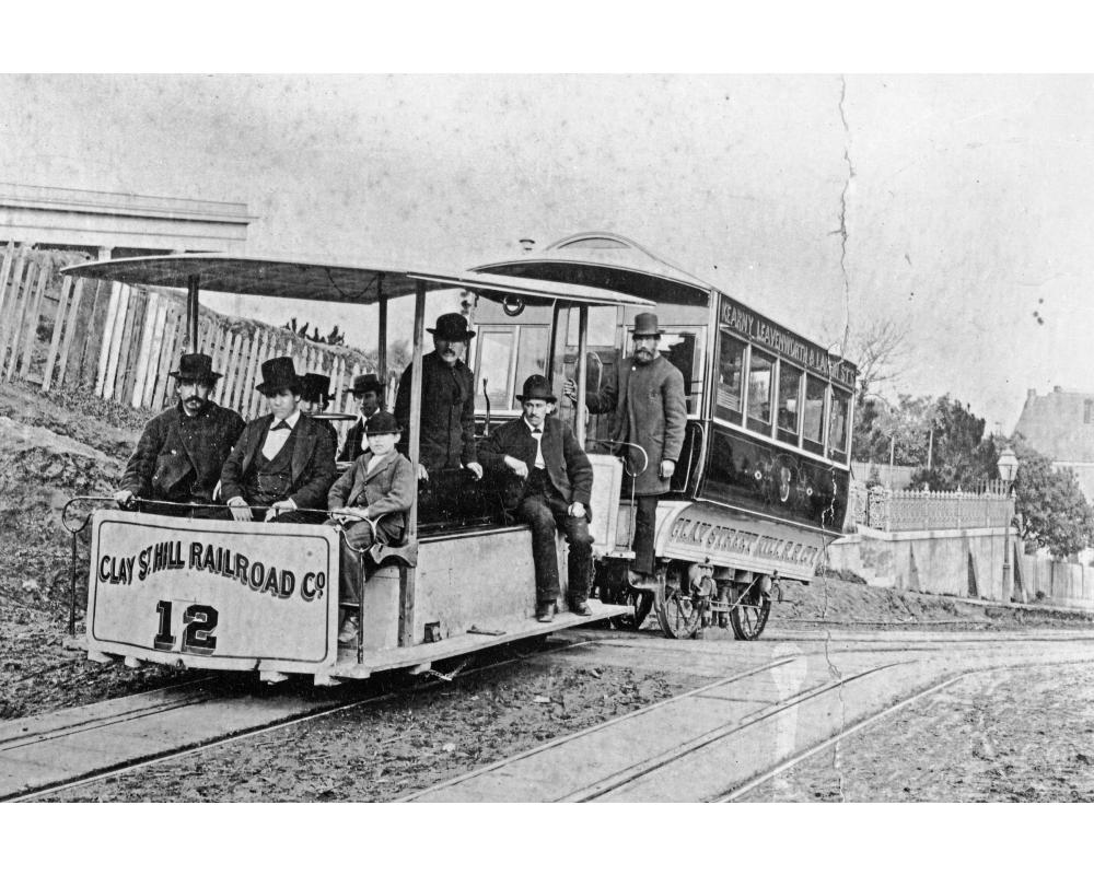 black and white photo of original cable train on clay street hill in 1873 with people on board.