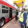 Muni Ambassador looks on as customer wearing a mask waits to board through the back after taking an essential trip for groceries