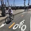 two people riding in a two-way protected bikeway that is marked by bicycle symbols on the roadway