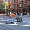 Two employees with equipment painting the road