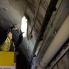 Crew member holding light by the tunnel ight. They seem to elevated by a lift. 