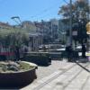 Person boarding train near large sidewalk planters and benches. 