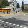 students using a crosswalk to cross clarendon avenue at panorama drive a bus is waiting in the intersection.