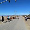 A road running alongside a beach with a crowd of people watching a band playing music.
