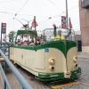 Cream and green open-air streetcar, a Boat Tram, drives near the Embarcadero. The operator waves.