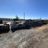 Gravel storage yard with bulky stored material and shrubbery