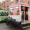 Two retro streetcars, one cream and green and one gray and red, pause during Muni Heritage Weekend 2023.