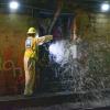 Two crew members wear yellow safety gear inside a Muni Metro tunnel as they flush standpipes for Fix-It Week.