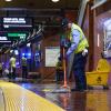 Custodian wearing a yellow vest and blue uniform mops the floor of a Muni Metro station as part of Fix-It Week.