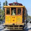 People board a yellow and tan historic streetcar during the 2024 Muni Heritage Weekend.
