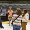 Three interns interviewing members of the public on a subway platform.
