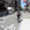 Person rides a bike on a separated bikeway that has hit-posts between the bikeway and moving vehicles.
