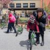 An adult helps a child balance on a bike in a school playground during an event.