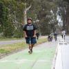 Youth riding a scooter on a green separated bikeway. 