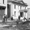 black and white photo of men working on rails in the street