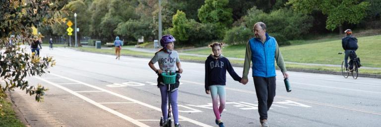 a family walking and scooting on car-free JFK Drive