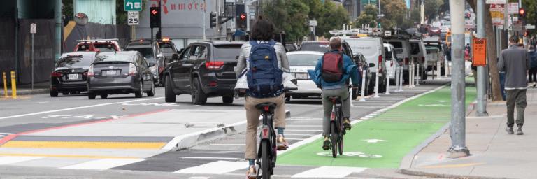 bicyclists riding in a bikeway protected by a transit boarding island and on-street parking