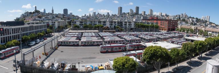 Kirkland Yard lot full of buses with city skyline in background