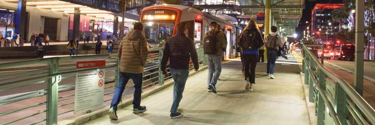 Muni riders boarding a train outside Chase Center at night