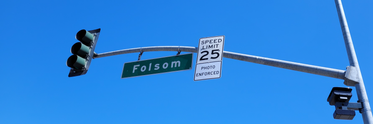 Sign post of Folsom street including a 25 mph speed limit and "Photo Enforced" with a camera attached