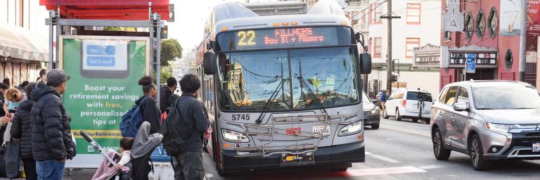 People waiting to board a 22 Fillmore bus at a bus shelter