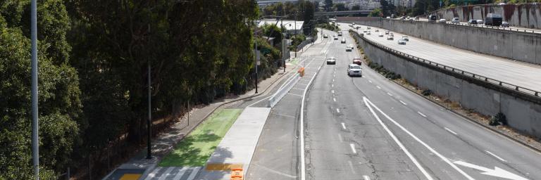 View of newly installed protected bike lane and concrete boarding island. Photo from the view of the pedestrian foot bridge looking to the east.