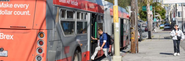 A rider boards the at the back door of the 8 Bayshore bus at the intersection of Geneva Avenue and Santos Street in San Francisco