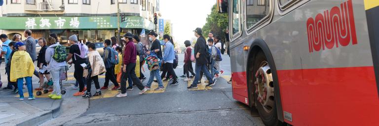 Students cross street in front of a Muni Bus