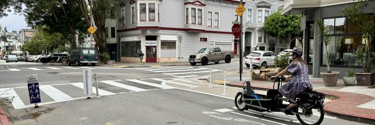Image of Noe Street with a person on a cargo bike approaching the 15th St intersection