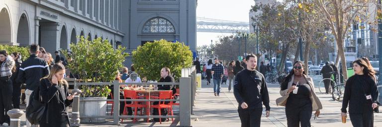 A photograph of people walking on the sidewalk outside the Ferry Building in San Francisco