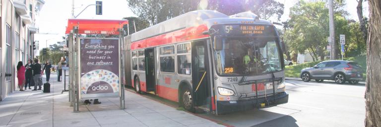 5R bus pulling up to a bus stop with a transit shelter