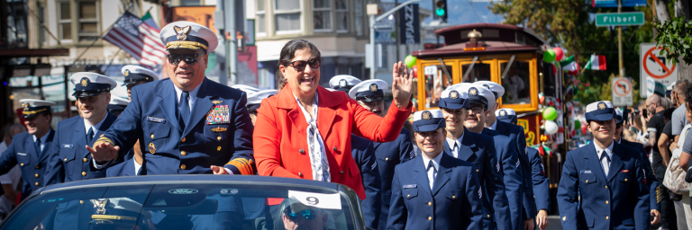 San Francisco Italian Heritage Parade on Columbus with people in uniform in the foreground and a immitation cable car behind