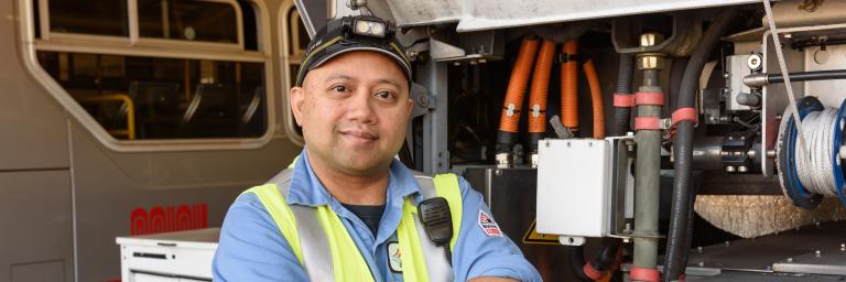 Muni Mechanic NRamos in front of a bus with it's engine access opened