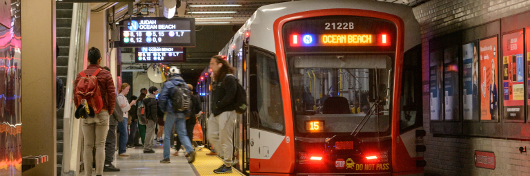 Busy Muni Metro platform with passengers getting of a train bound for Ocean Beach