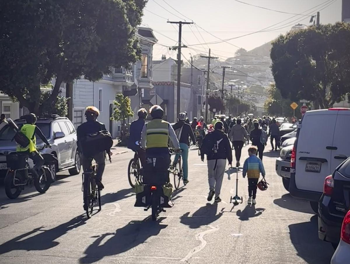 People on bicycles and walking down a street People on bicycles and walking down a street