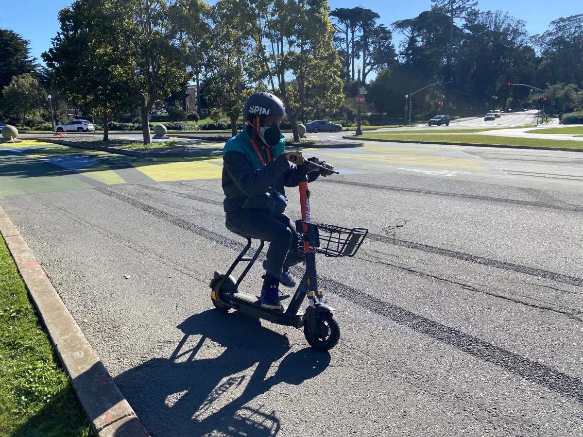 Person rides a shared scooter that features a basket through Golden Gate Park. Person rides a shared scooter that features a basket through Golden Gate Park.
