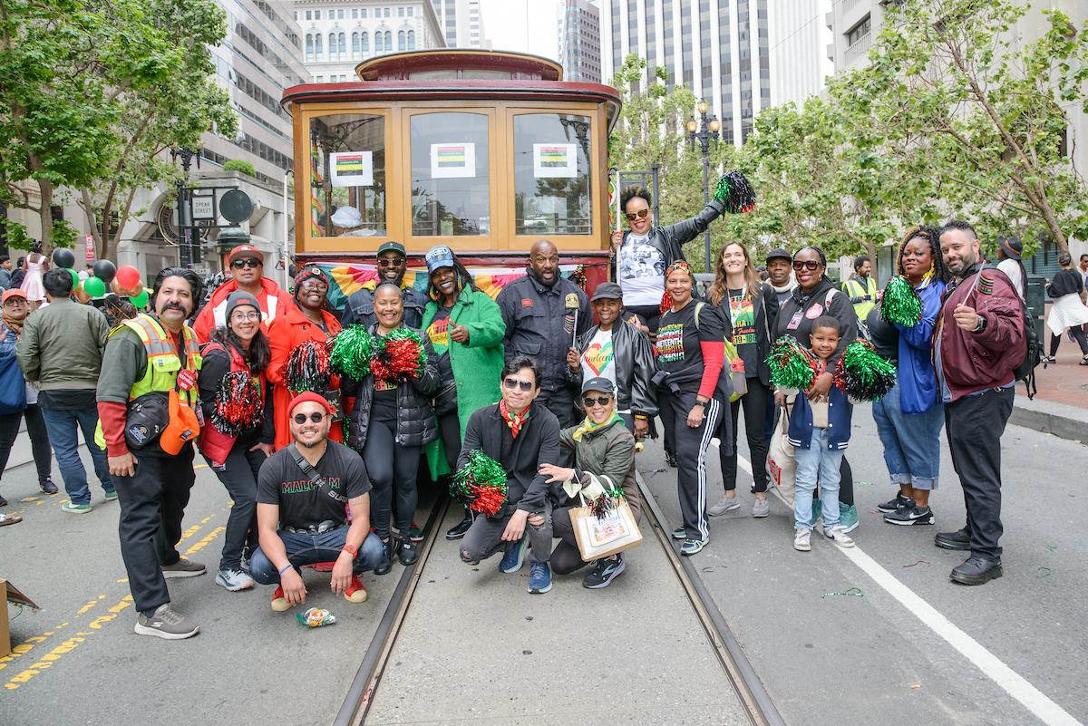 People standing in the street in front of a motorized cable car.
