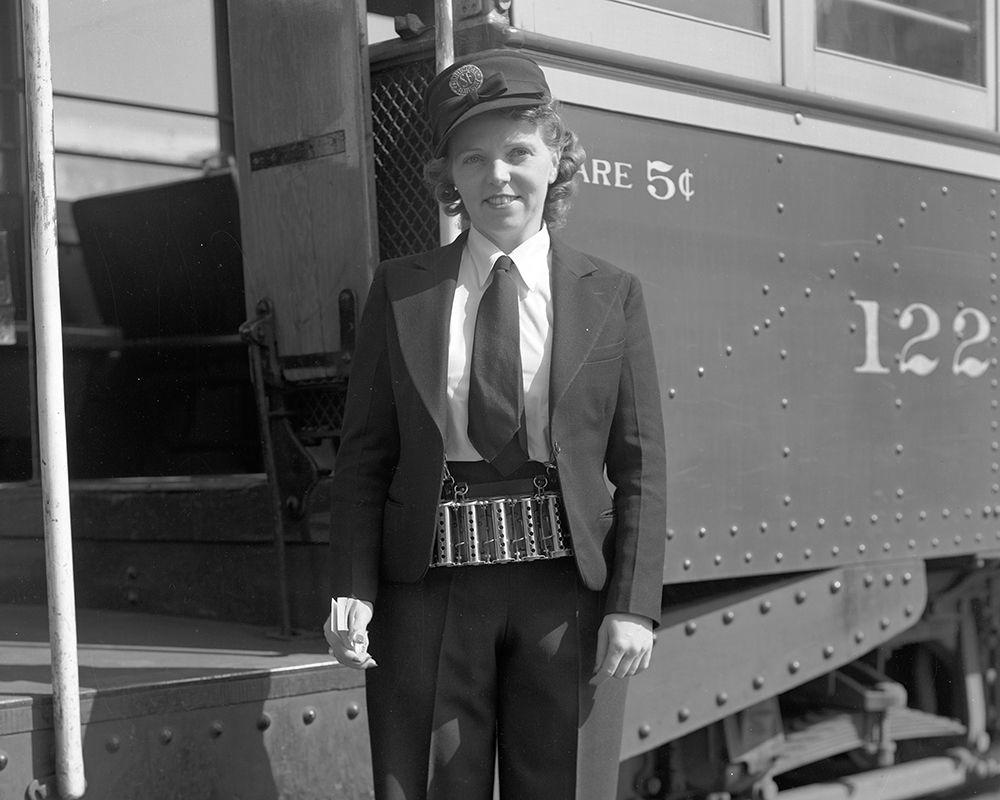 Person in uniform holding paper transfers and change maker standing in front of streetcar Person in uniform holding paper transfers and change maker standing in front of streetcar
