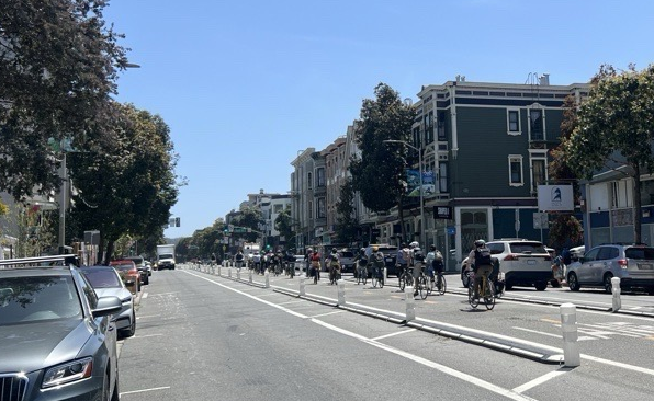 People bike on the center-running bikeway on Valencia Street. People bike on the center-running bikeway on Valencia Street.